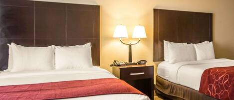 A hotel room with two beds, a nightstand with lamps, and a carpeted floor.