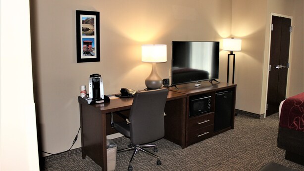 A hotel room with a desk, chair, television, and two lamps. - Comfort Suites Huntersville near Lake Norman (Huntersville)