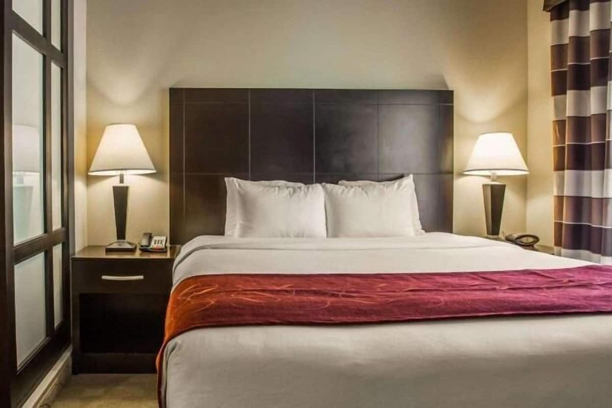 Une chambre d’hôtel avec un grand lit, deux tables de chevet avec des lampes, une chaise et un tableau encadré au mur.