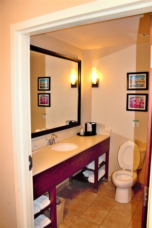 Une salle de bain avec un double lavabo, des toilettes, un grand miroir et deux appliques murales.