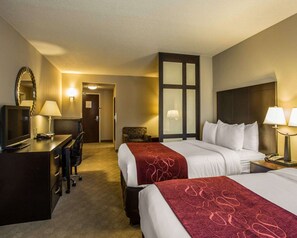 Een hotelkamer met twee bedden, een bureau, een stoel, een televisie en een spiegel.