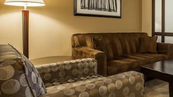 A room with a sofa, a patterned armchair, a lamp, and a framed picture on the wall.