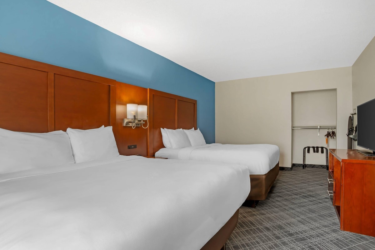 Een hotelkamer met twee bedden, een bureau, een televisie en een kapstok.