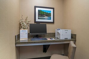 Een bureau voor zakelijk gebruik met een computer, een printer en een ingelijst foto aan de muur.