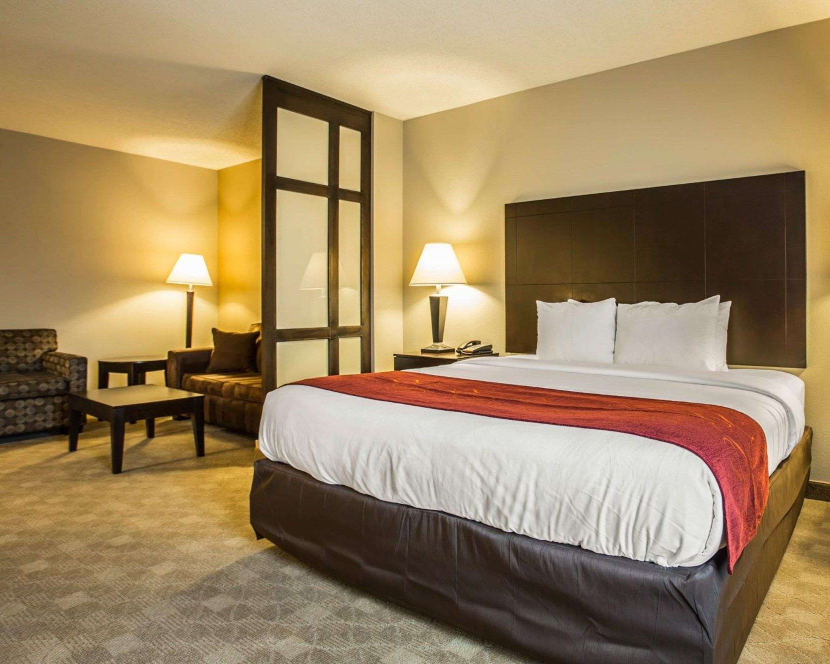 A hotel room with a large bed, two bedside tables, a chair, and a desk.