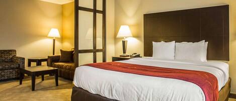 Una habitación de hotel con una cama grande, dos mesitas de noche, una silla y un escritorio.