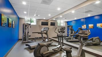 Ein Fitnessraum mit Cardiogeräten, Spiegeln und Kunstwerken an den Wänden.