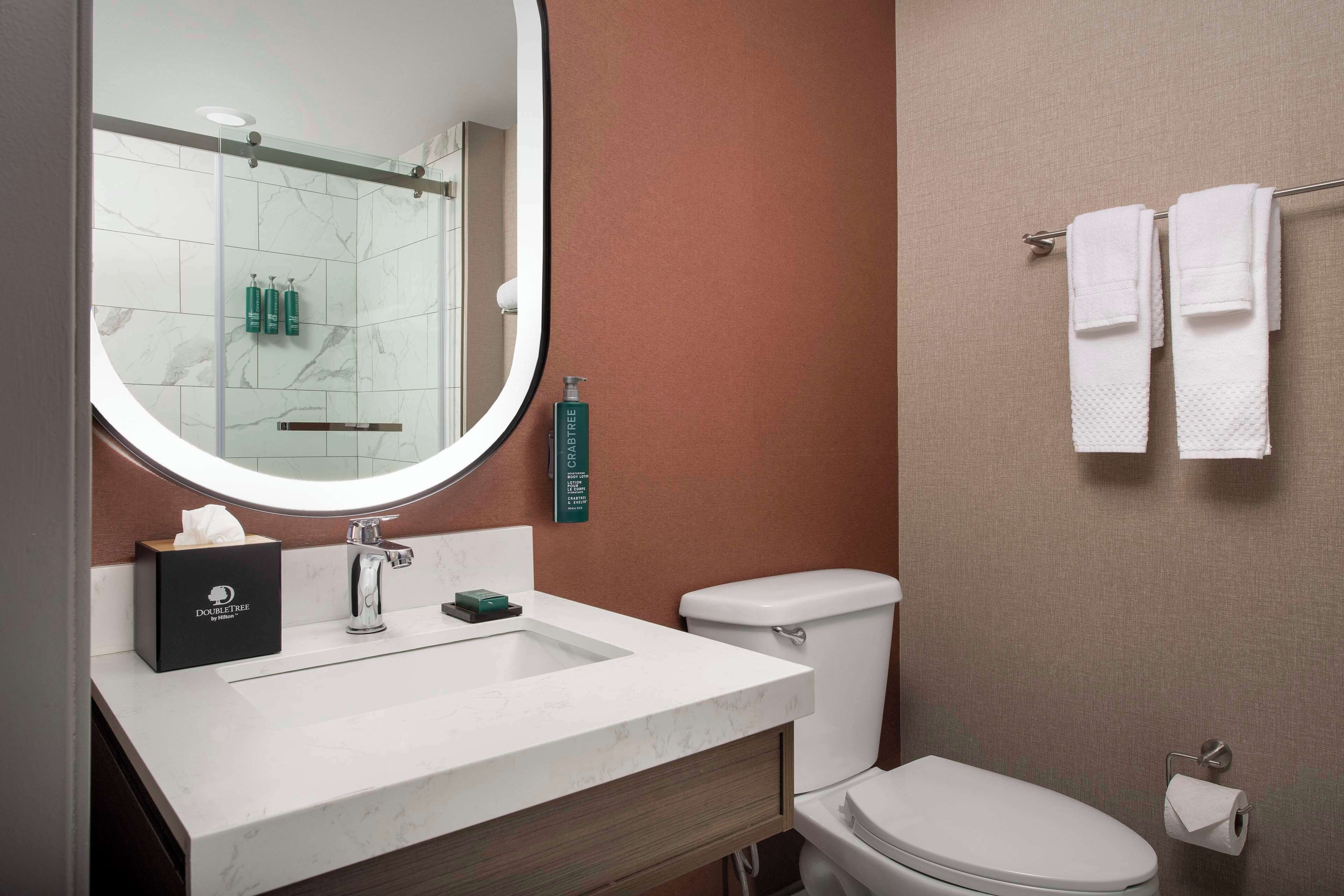 Une salle de bain avec un lavabo blanc, un miroir, des toilettes et un porte-serviettes.