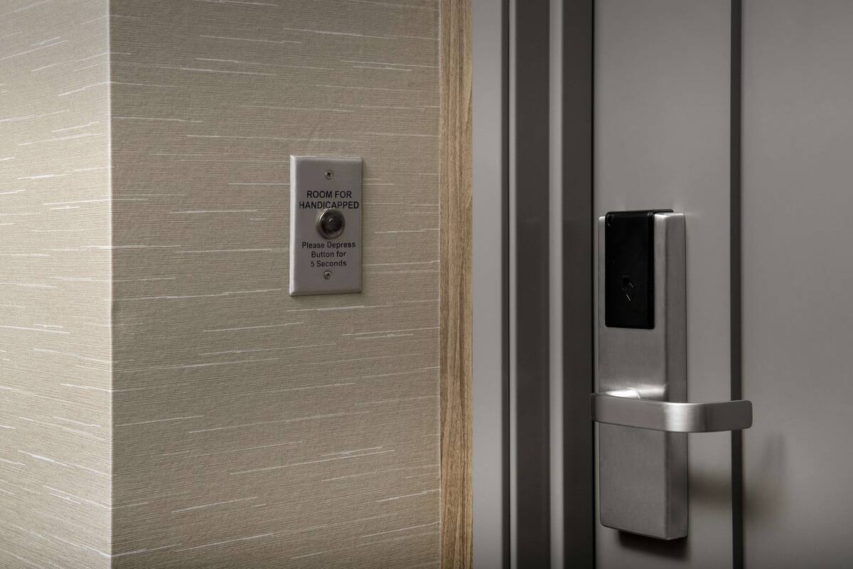 A door with a sign indicating a room for handicapped individuals and a button to press for 5 seconds.