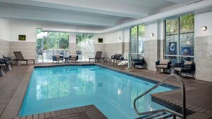 An indoor swimming pool with clear blue water, surrounded by lounge chairs and a seating area with tables. - Doubletree by Hilton Chattanooga Hamilton Place (Chattanooga)