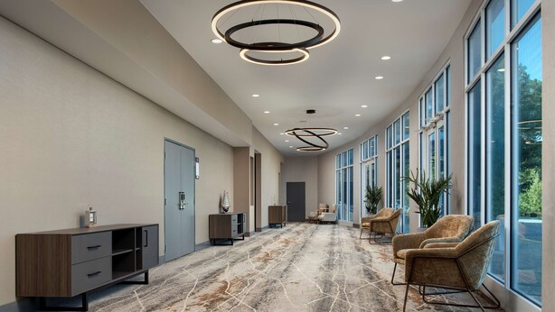 A spacious hallway with a marble floor, modern lighting fixtures, and large windows offering a view of the outdoors. - Doubletree by Hilton Chattanooga Hamilton Place (Chattanooga)