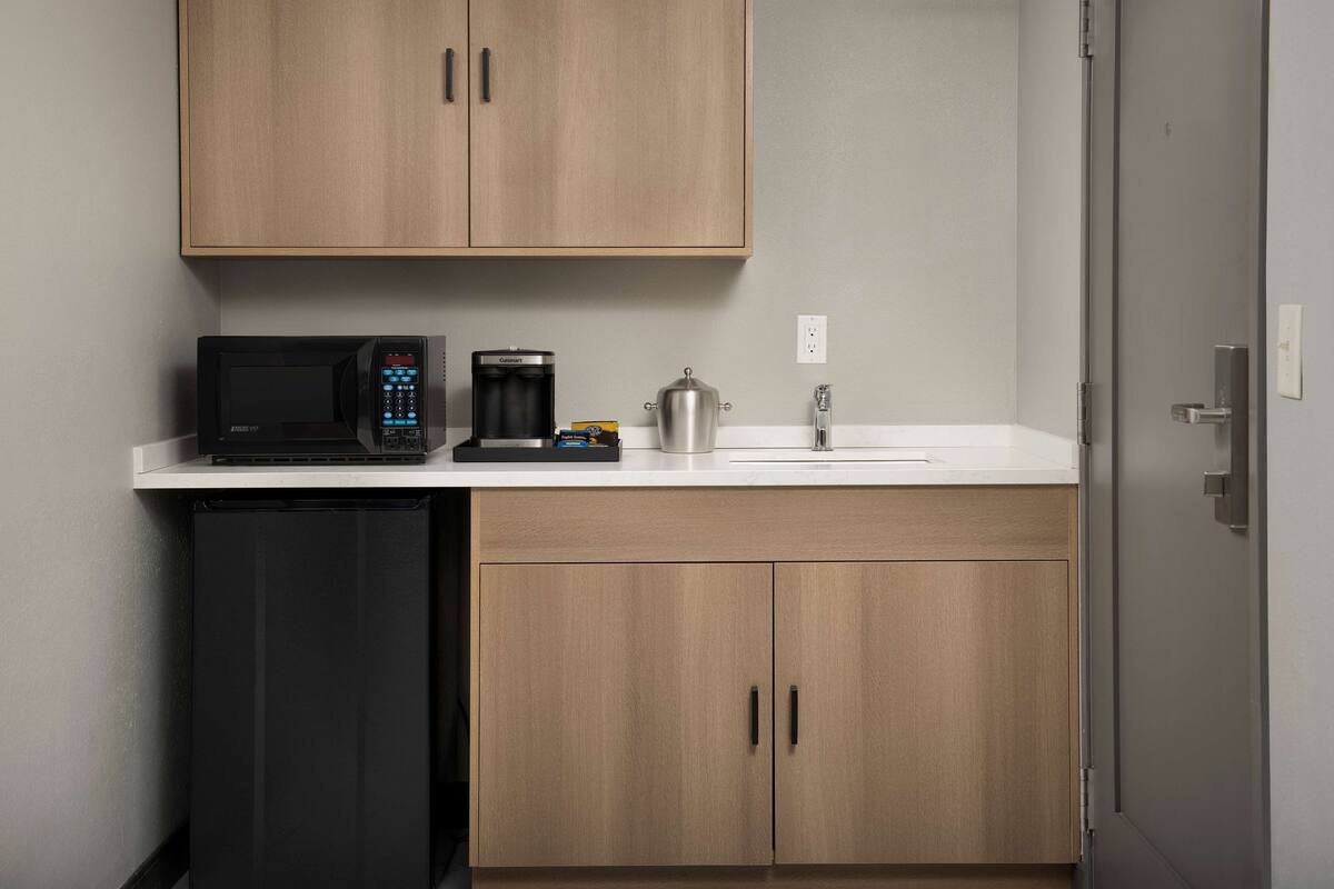 A compact kitchenette with a microwave, coffee maker, and a small refrigerator.