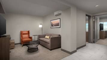 A modern living room with a sofa, armchair, coffee table, and a flat-screen TV.