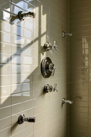 A bathroom with multiple faucets and a showerhead on a tiled wall.