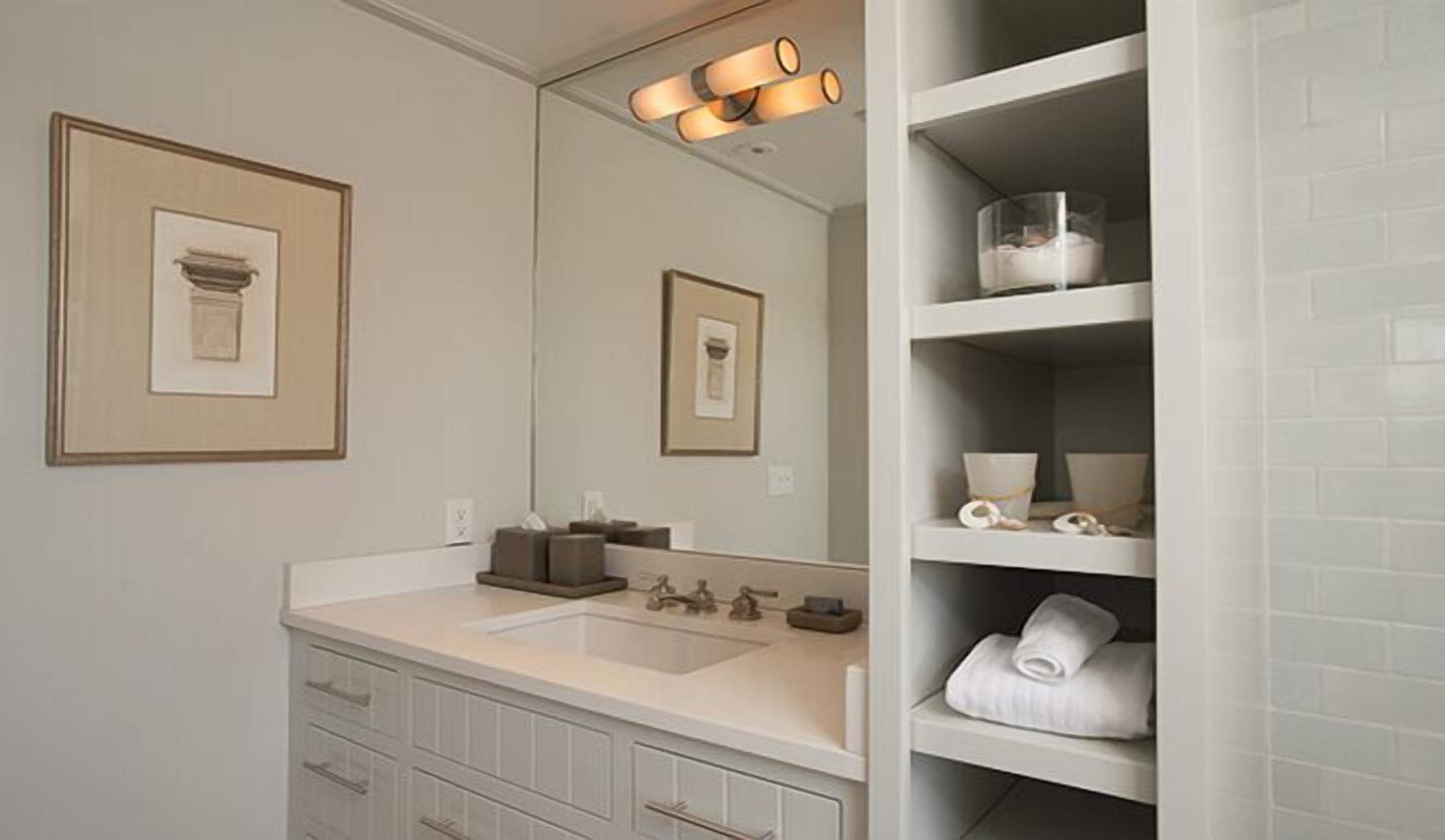 Une salle de bain avec un meuble-lavabo à deux vasques, un miroir et des étagères contenant des articles de toilette.