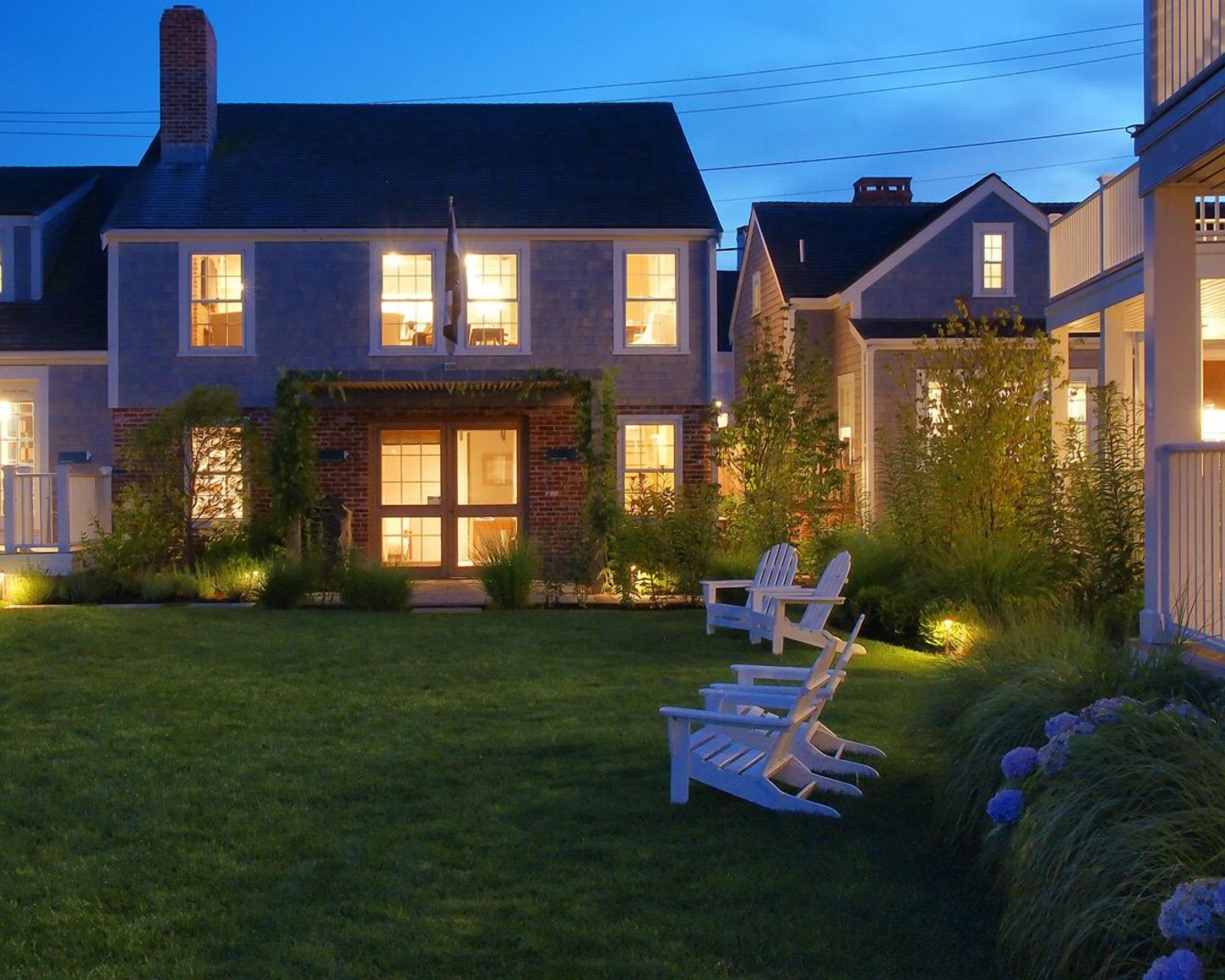 A two-story house with a well-maintained lawn and outdoor seating area.
