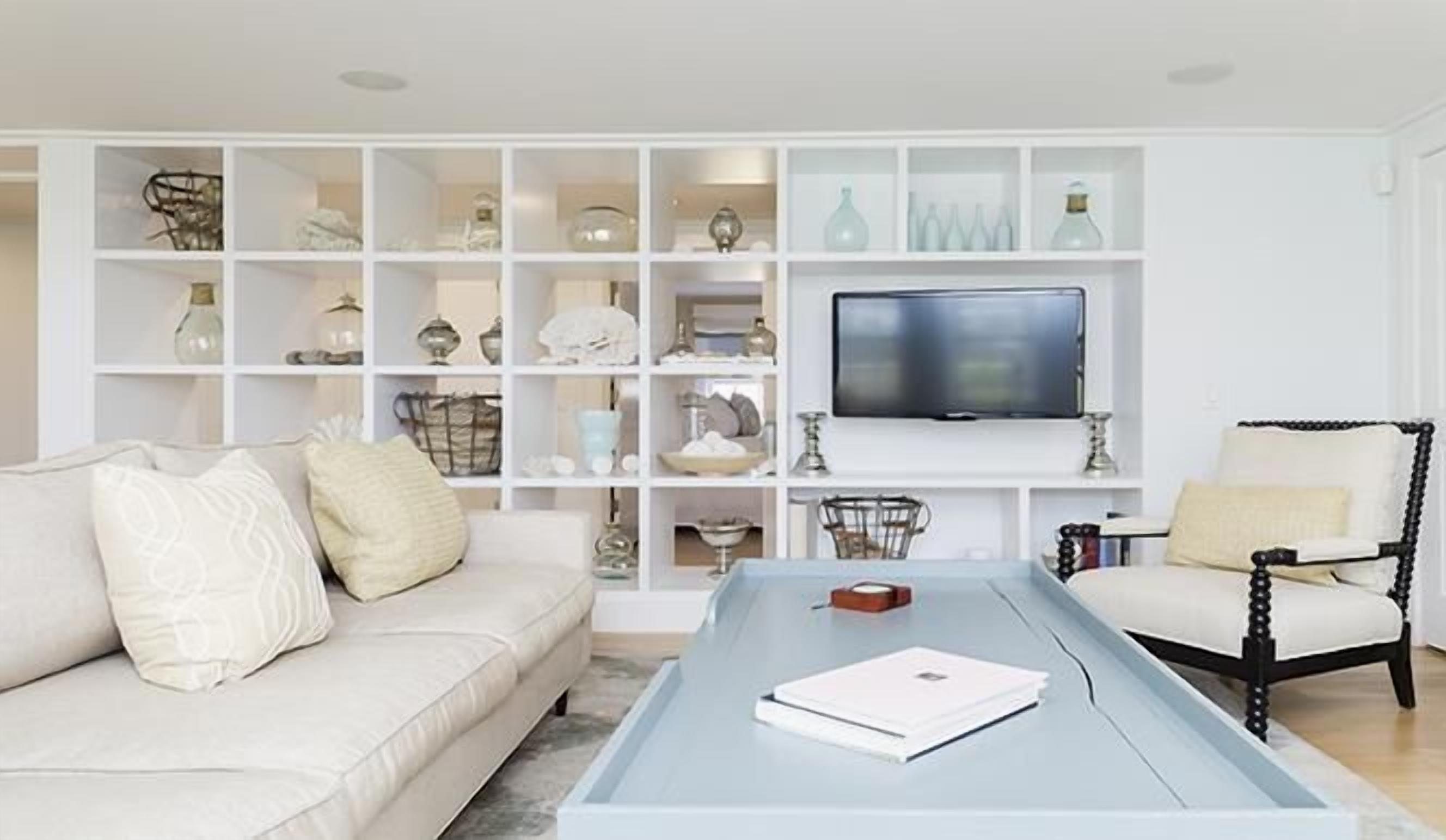 A living room with a white sofa, a coffee table, and a TV on a white stand.