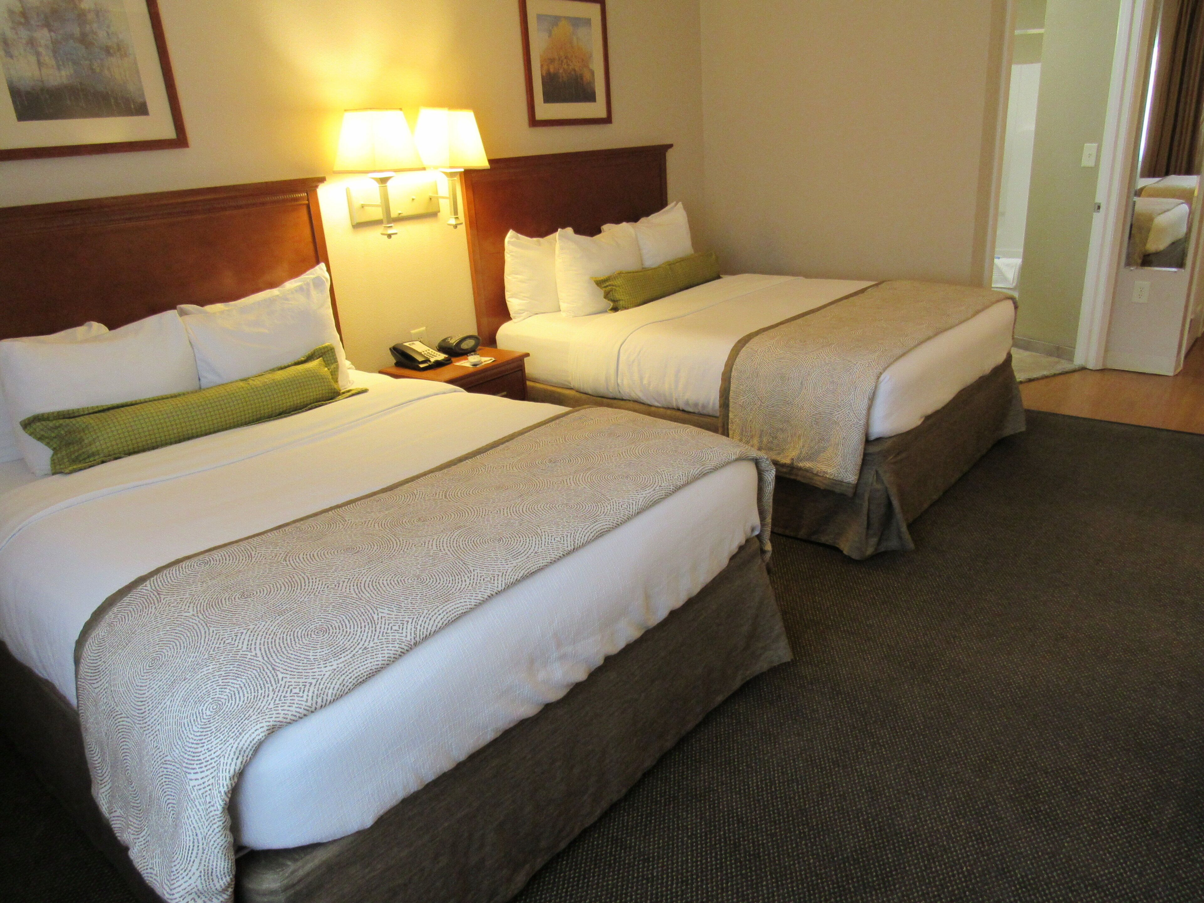 Two double beds with headboards, bedside lamps, and a telephone on a nightstand.