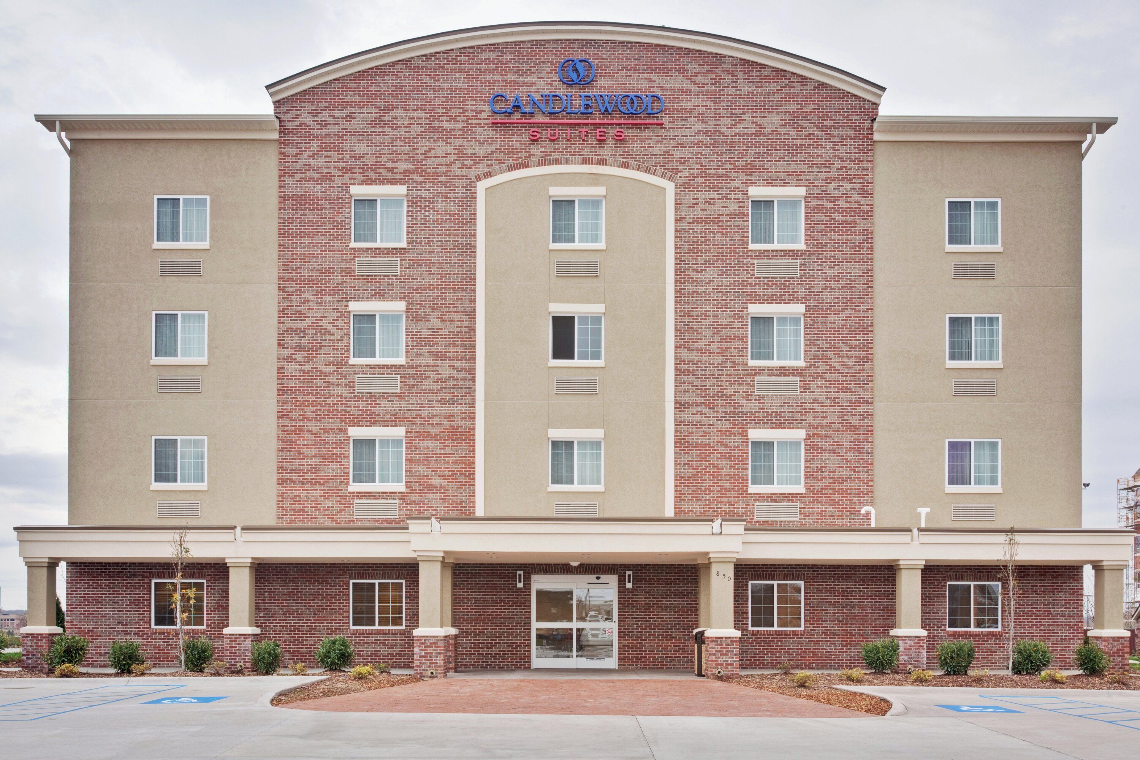 Un hôtel à plusieurs étages, doté d’une façade en briques, d’une entrée principale et d’un parking comprenant des places réservées aux personnes handicapées.