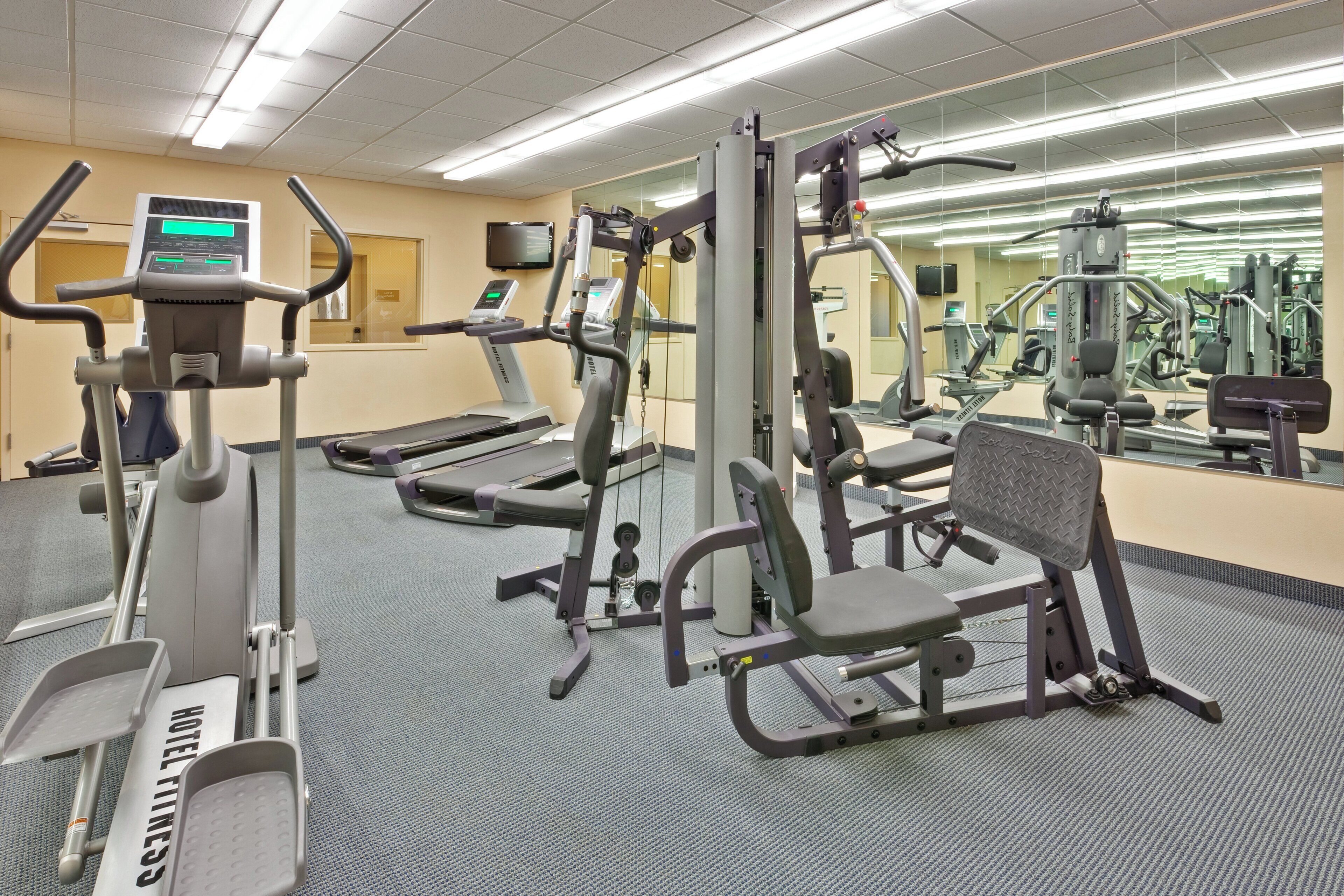Een hotel fitnessruimte met loopbanden, elliptische trainers en gewichten.