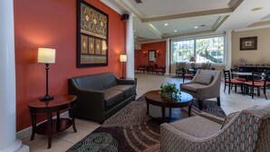 A spacious lobby with a high ceiling, a large window, and a seating area with a sofa, armchairs, and a coffee table. - Travelodge by Wyndham Lakeland (Lakeland)