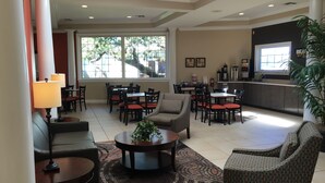 A spacious lobby with multiple seating areas, including sofas and chairs, a coffee station, and a reception desk. - Travelodge by Wyndham Lakeland (Lakeland)