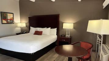 Een hotelkamer met een groot bed, twee nachtkastjes met lampen, een kleine ronde tafel met stoelen en een wandradiator.