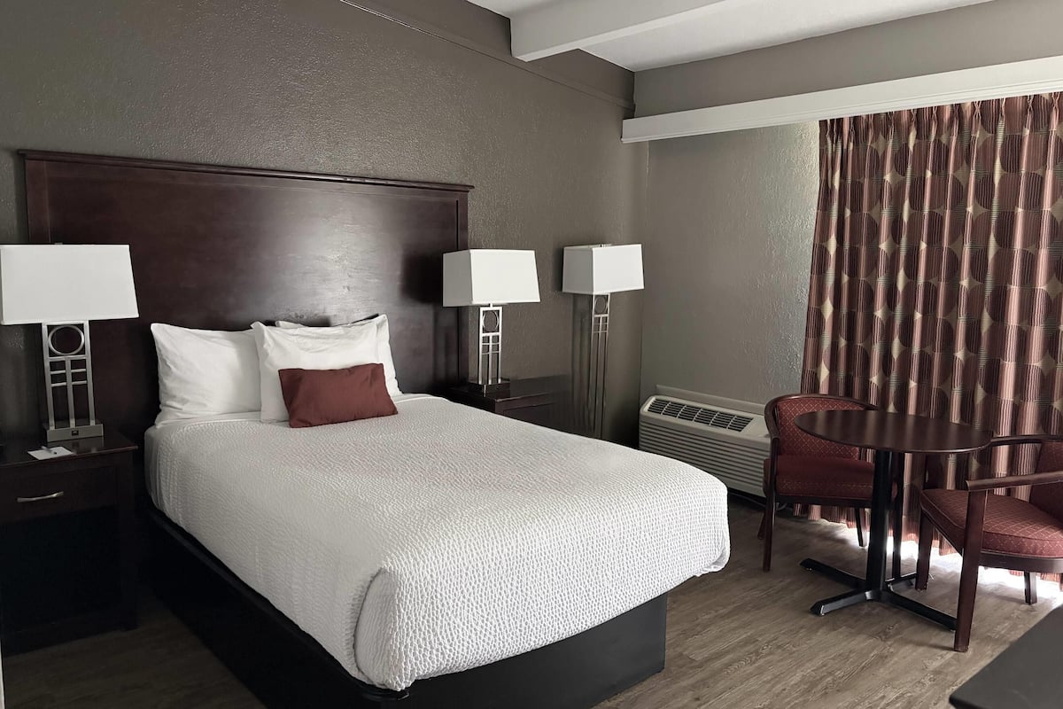 Habitación de hotel con una cama grande, dos lámparas de noche, un escritorio con una silla y un equipo de aire acondicionado.