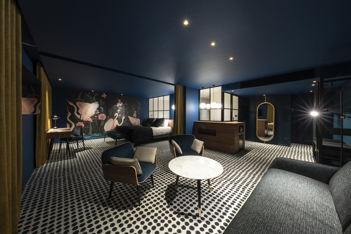 A modern room with a patterned floor, a sofa, armchairs, a small table, and a large mirror.