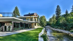 Een modern huis met twee verdiepingen, een glazen gevel, een stenen fundering en een verzorgd gazon.