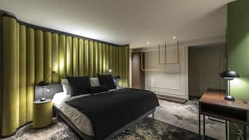 A modern hotel room with a large bed, a desk, and a green accent wall.