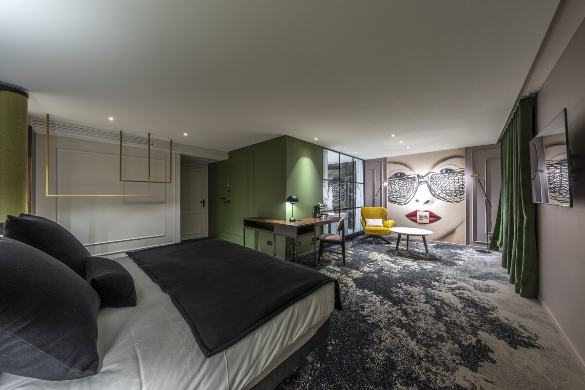 A modern bedroom with a bed, desk, and chair, and a large mirror with a unique design.