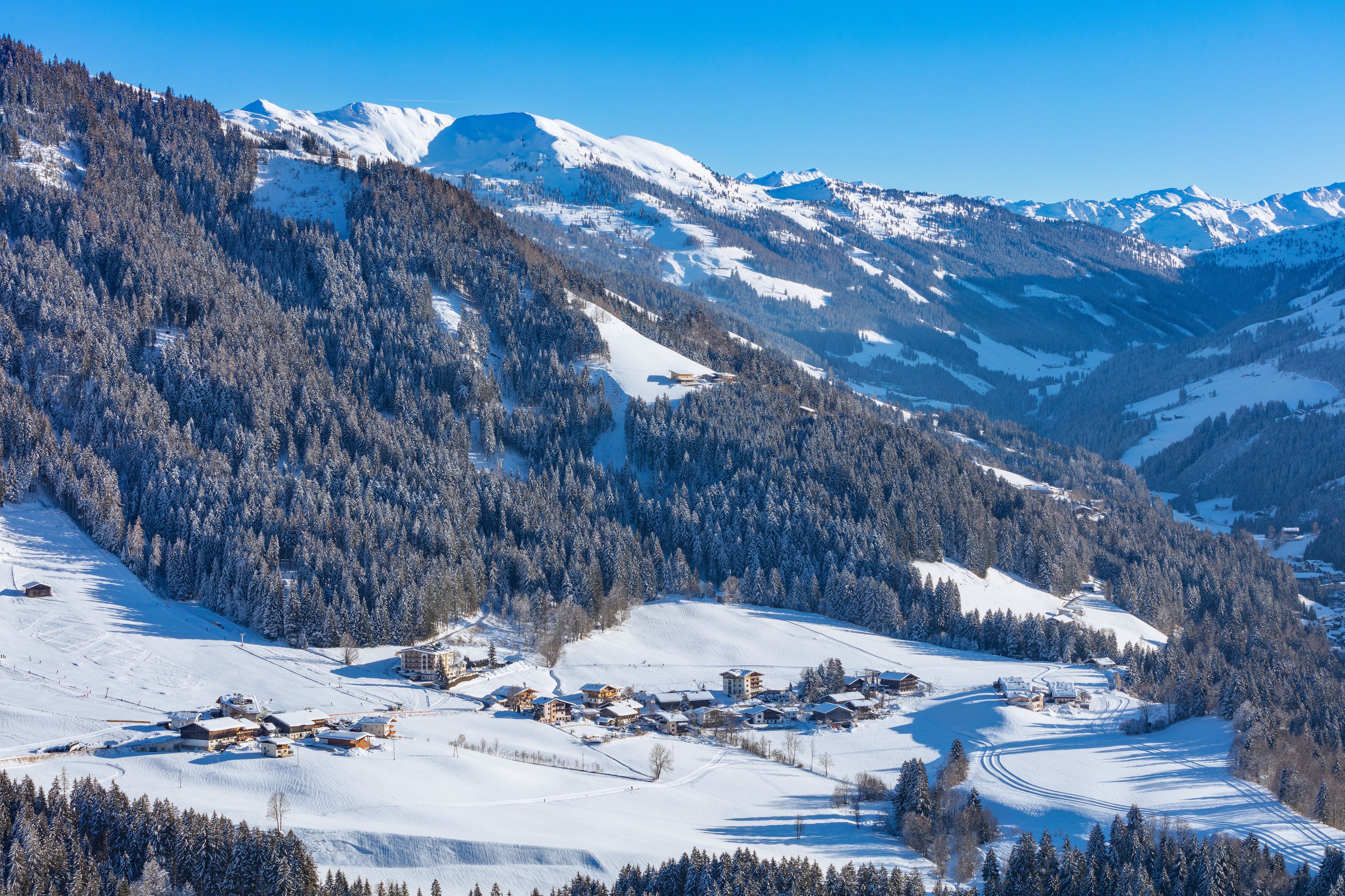 Un village enneigé, avec des bâtiments et une montagne en arrière-plan.