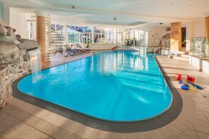 Una piscina techada, sillones reclinables de piscina