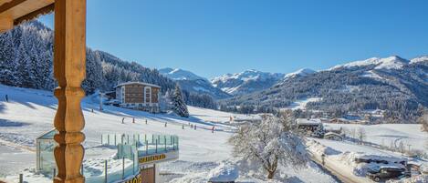Ein Hotel mit Blick auf eine Skipiste, Holzbauweise und einem Schild mit der Aufschrift 'Hallenbad'.