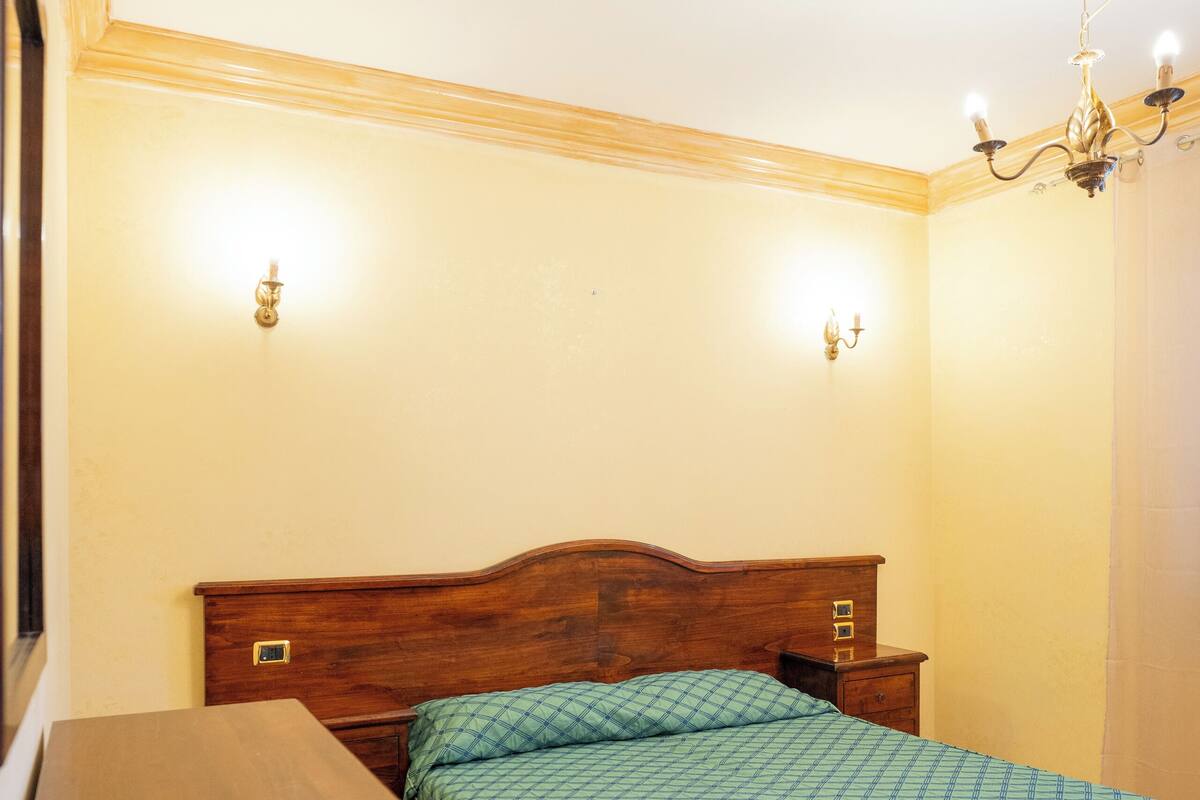 A bedroom with a wooden bed, bedside tables, and a nightstand.