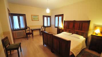 A bedroom with a wooden bed, a desk, a chair, and a radiator.