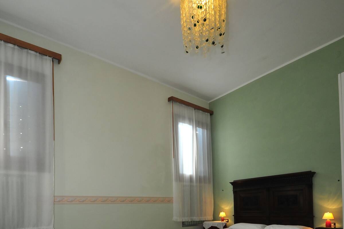A bedroom with a bed, a nightstand, a chair, and a decorative ceiling light.