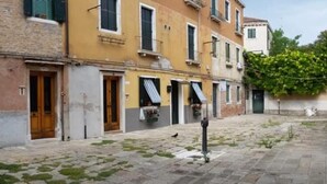 Una calle estrecha flanqueada por edificios con fachadas de ladrillo y enlucido, puertas de madera y pequeños balcones.