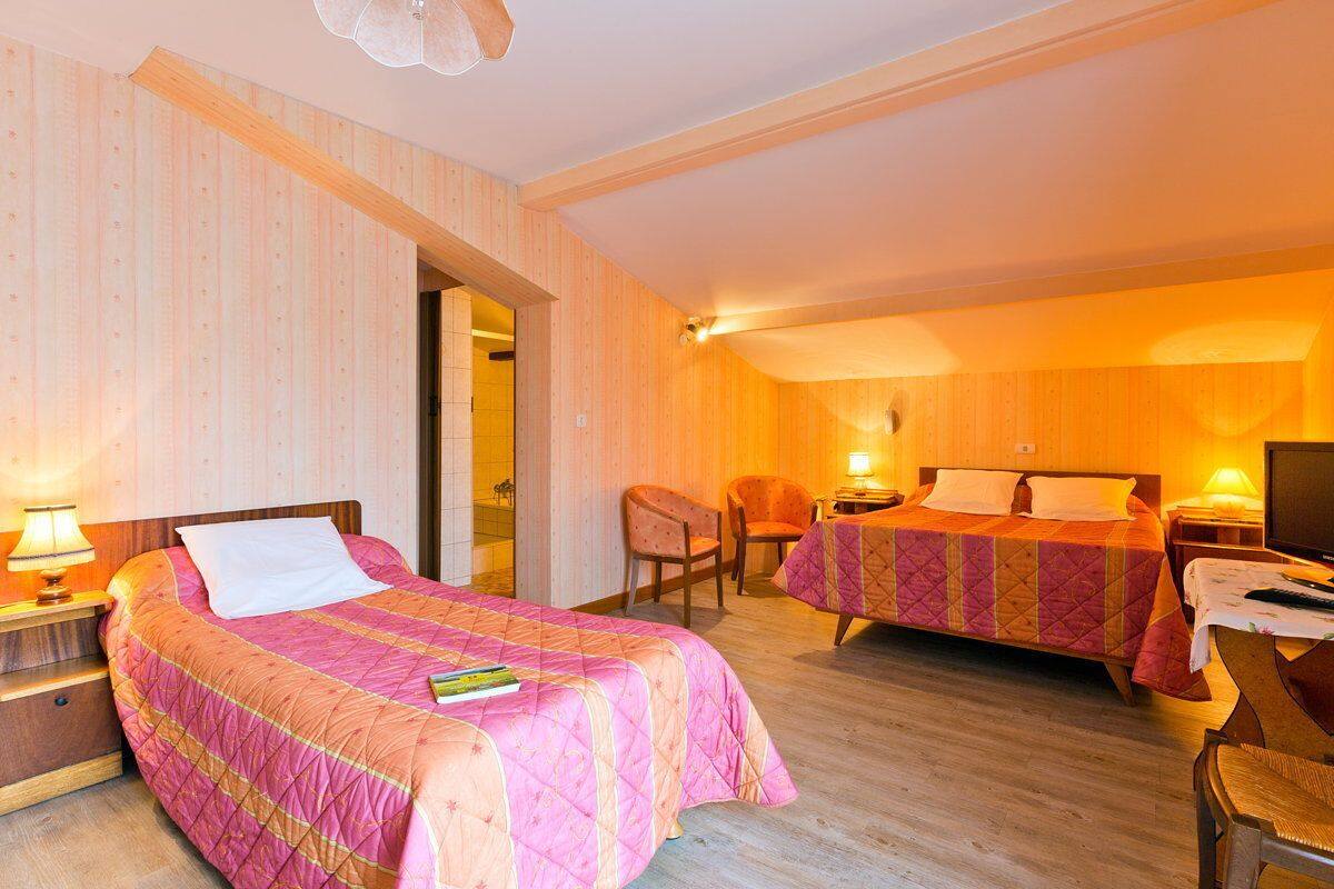 Ein Hotelzimmer mit zwei Betten, Holzboden und einem Fernseher.