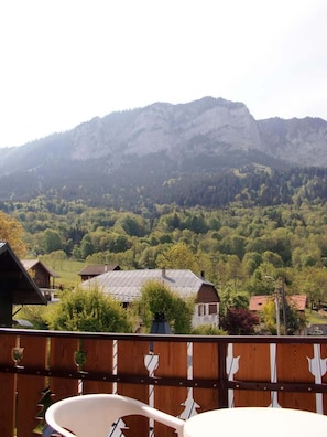 Un balcon avec vue sur une montagne et une vallée boisée.