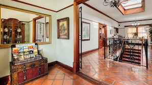 A spacious lobby with a wooden floor, a large mirror, a vintage trunk, and a staircase with a wrought iron railing. - Berg en Zee Guesthouse (Cape Town)
