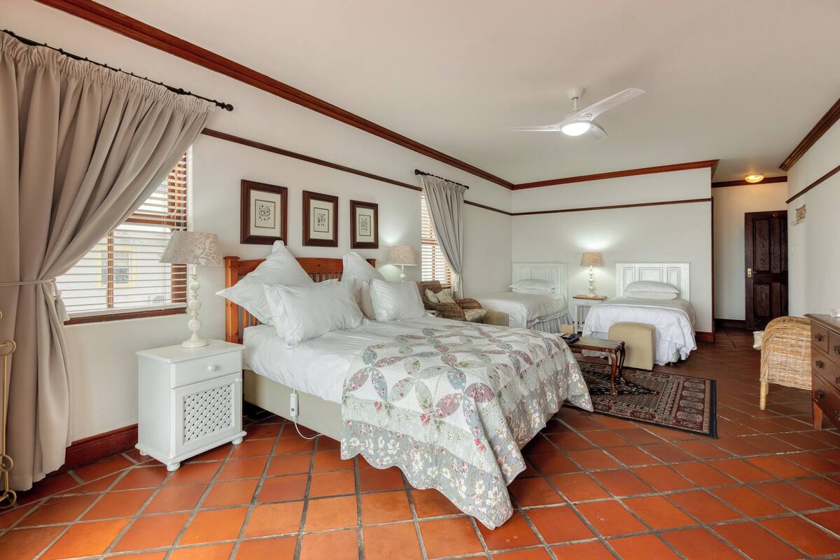 Une chambre avec deux lits, une table de chevet, une commode et un ventilateur de plafond.