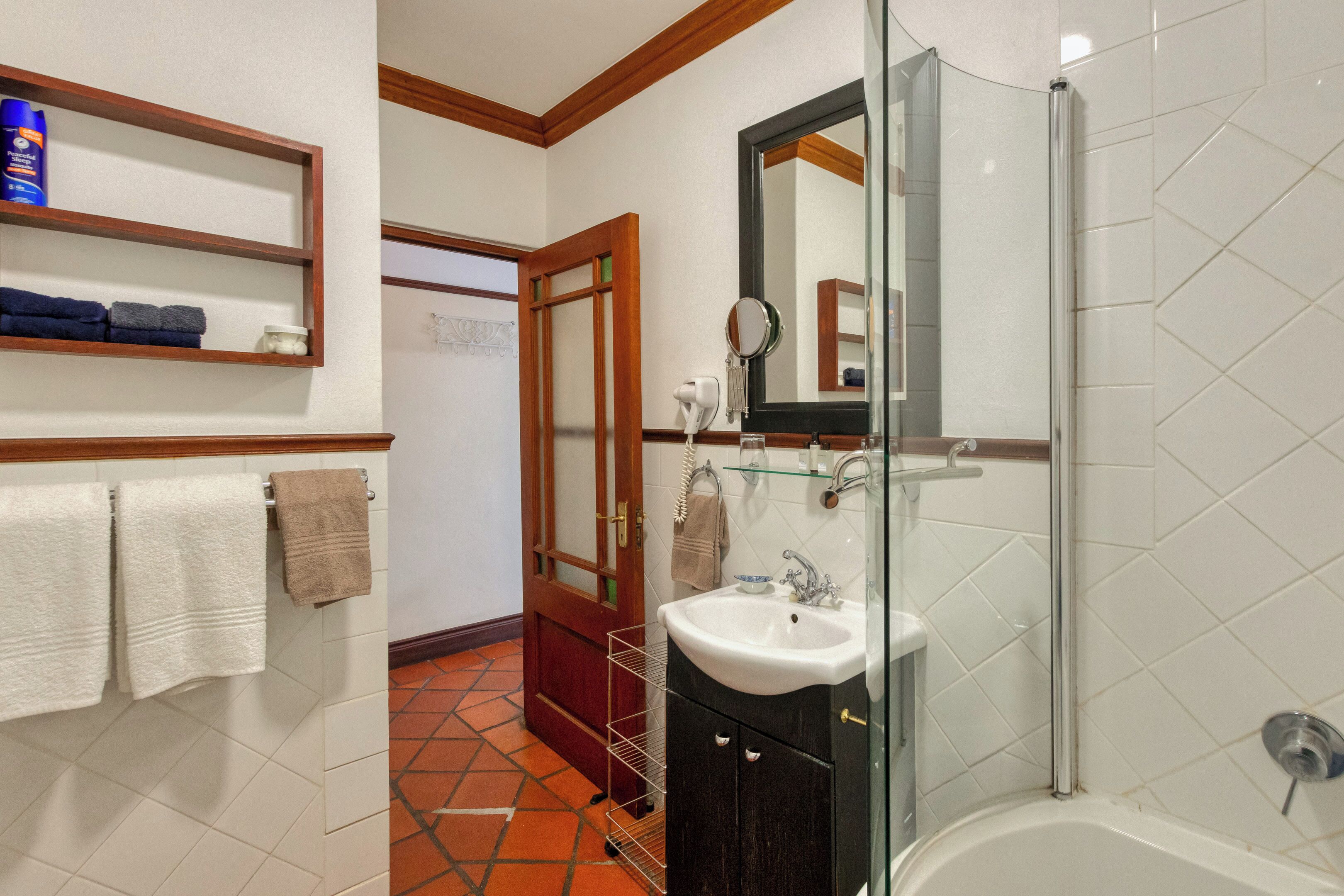 Un baño con lavamanos blanco, espejo y cabina de ducha de vidrio.