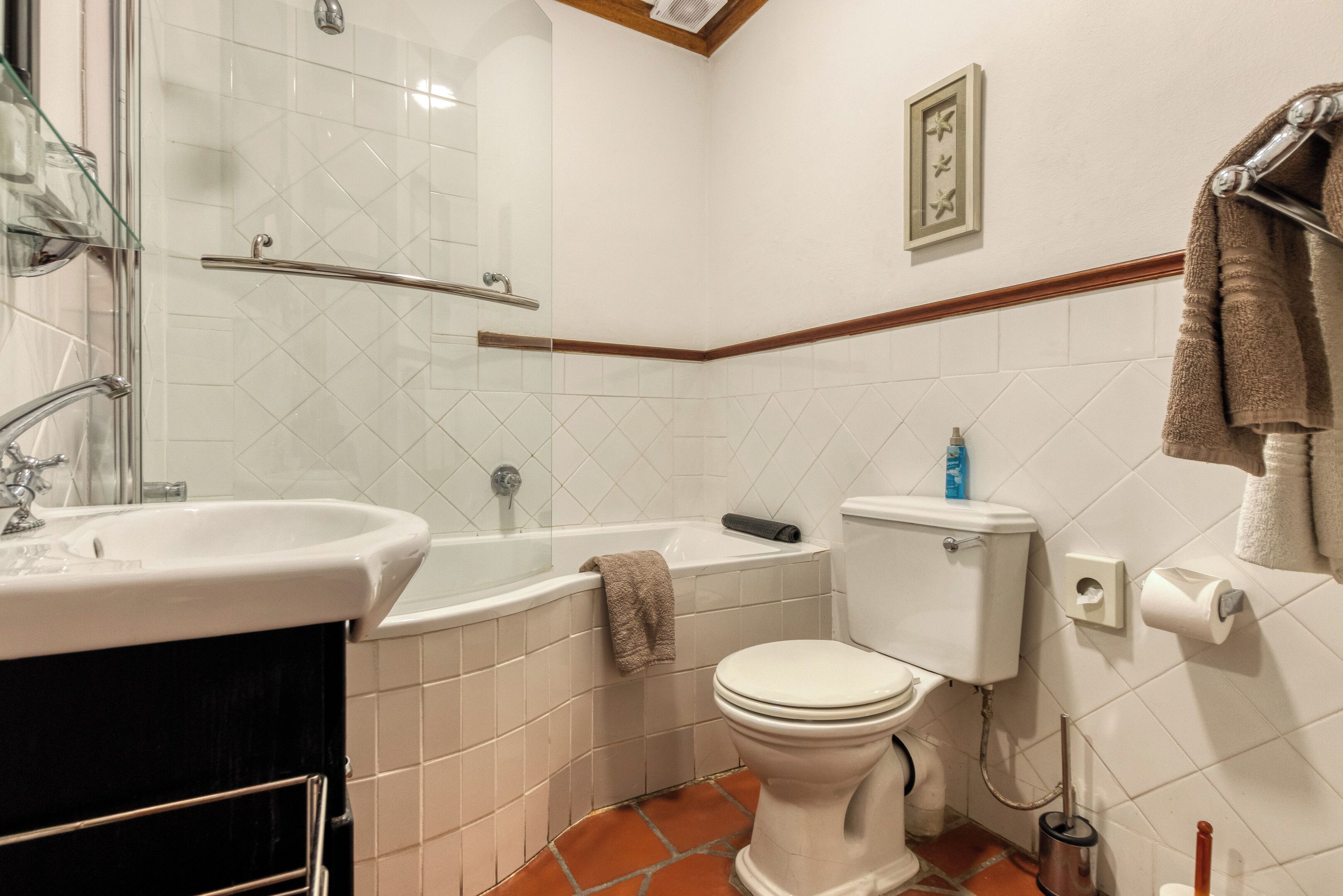 Un baño con lavamanos blanco, bañera, inodoro y cabina de ducha de cristal.