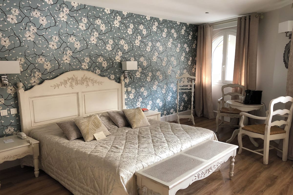 Un dormitorio con una cama grande, mesitas de noche, un escritorio y una silla.