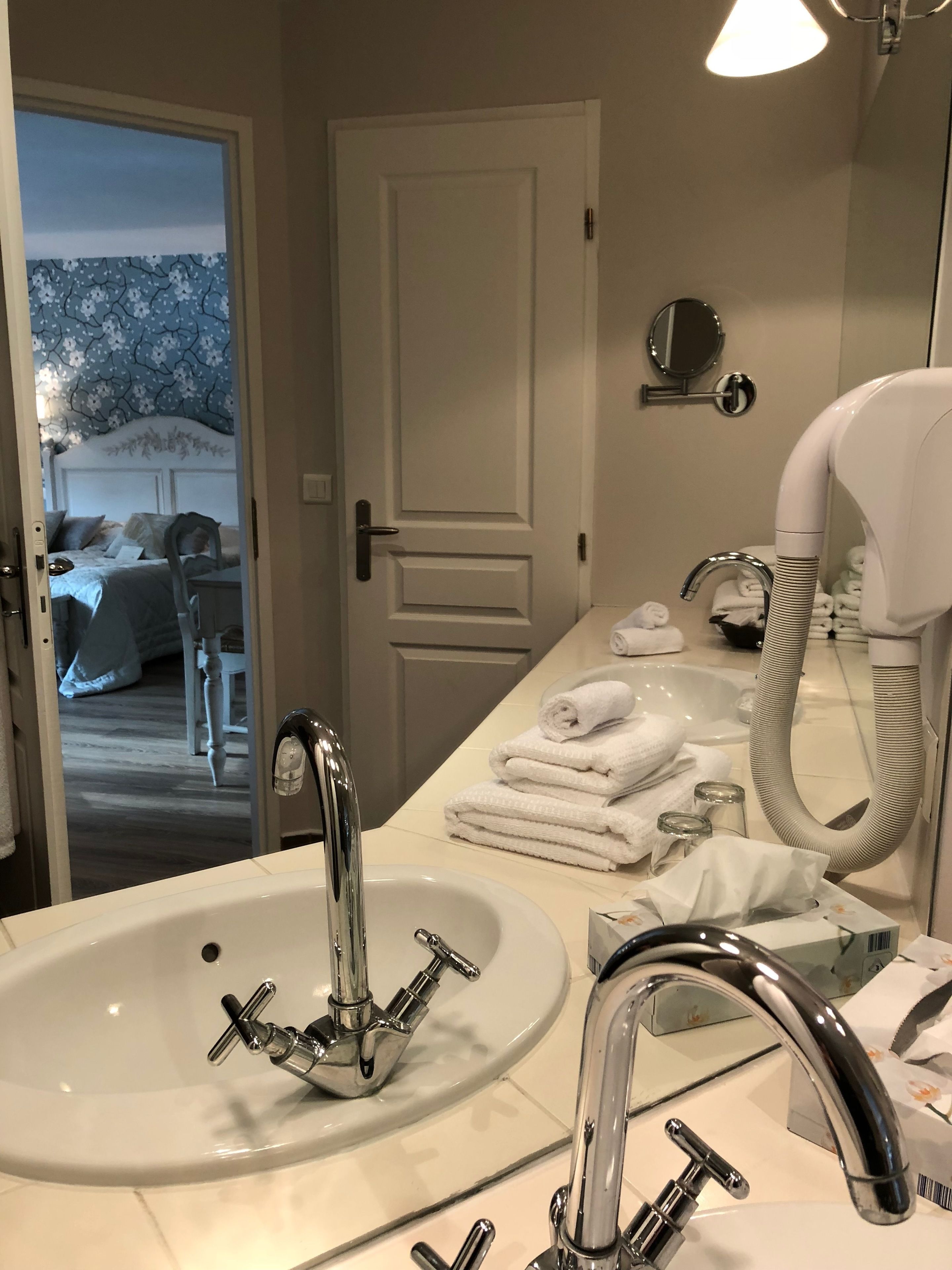 Un baño con un lavabo blanco, grifos cromados, un perchero y un espejo.