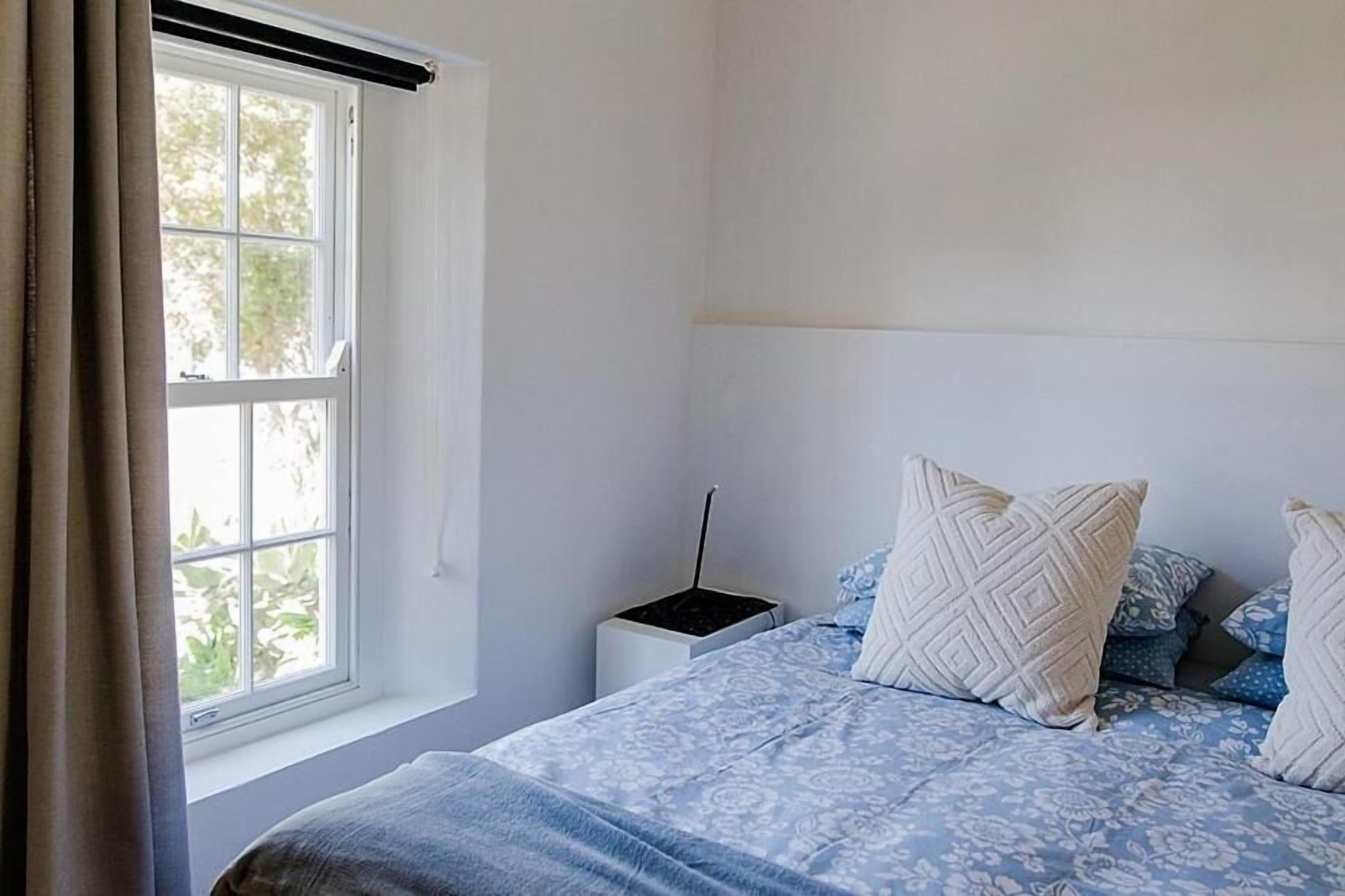 A bedroom with a bed, a nightstand, and a window with curtains.