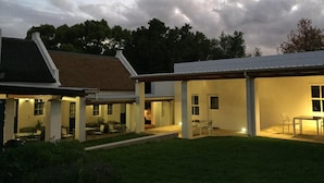 A modern house with a covered patio area, a lawn, and a cloudy sky. - La Sosta Restaurant & Guest House (Swellendam)