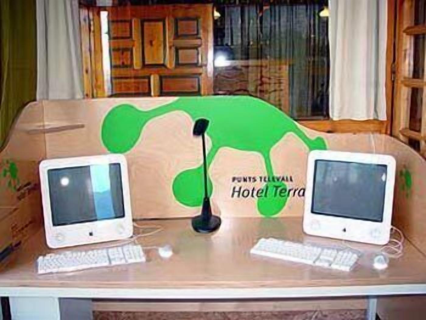 Un bureau avec deux écrans, un clavier et un microphone. L’arrière-plan comprend un panneau en bois et une fenêtre avec des rideaux.